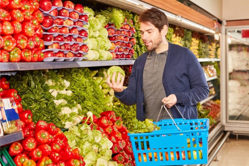 Homem jovem escolhendo frutas e legumes